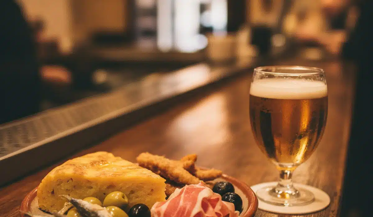 Plato de tapas variadas y una caña en un bar de Granada